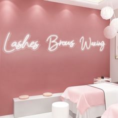 there is a pink wall with the words lashes bros wrong on it and two tables in front