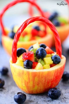 fruit salad in orange baskets with blueberries and raspberries on the side, ready to be eaten