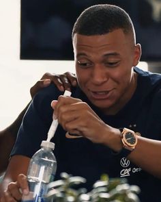 a man holding onto a water bottle while sitting at a table