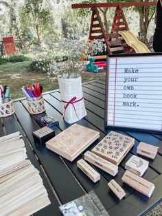 a table topped with lots of different types of cards and envelopes next to a sign that says make your own book mark