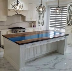 a kitchen with white cabinets and marble counter tops, along with an island in the middle