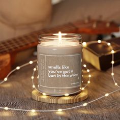 a lit candle sitting on top of a wooden table next to a string of lights