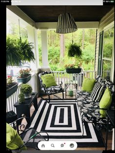 the porch is decorated with black and white striped rugs, green pillows, and potted plants