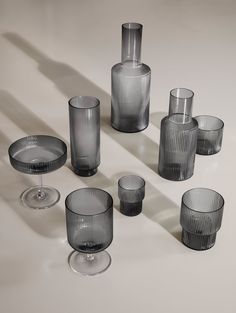 a group of glass vases sitting on top of a white table next to each other