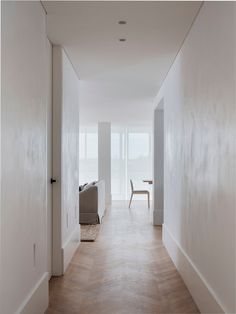 an empty hallway with white walls and wood flooring