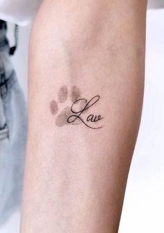 a woman with a tattoo on her arm that reads love and has paw prints all over it