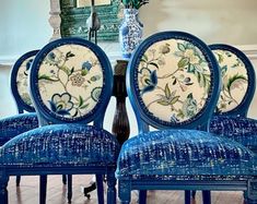 three blue chairs sitting next to each other in front of a table with flowers on it