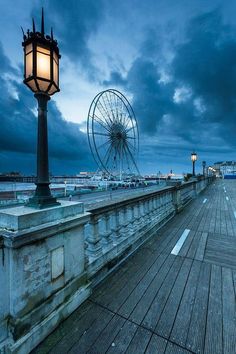 a street light sitting on the side of a wooden pier next to a ferris wheel