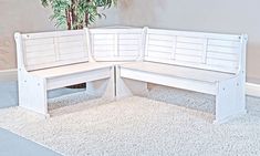 a white bench sitting on top of a carpeted floor next to a potted plant