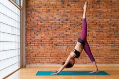 a woman is doing yoga in front of a brick wall with her legs up and hands behind her head