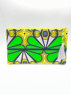 This beautiful graphic pattern clutch is great for the spring & summer seasons!  The beautiful green, yellow, silver, white, and black pattern makes a statement!  It measures 12 inch Width X 7 1/2 inch Length perfect for your essentials and more.  It has a yellow zipper for closure adorned with a silver gray 3 1/2 inch tassel adorned with green and yellow wooden beads.  The inside is lined in green along with an inside pocket. Yellow Rectangular Clutch For Summer, Yellow Rectangular Summer Clutch, Trendy Green Rectangular Clutch, Green Clutch Pouch For Daily Use, Trendy Green Clutch As A Gift, Trendy Green Clutch As Gift, Trendy Green Clutch For Gift, Trendy Yellow Rectangular Pouch, Trendy Green Pouch Clutch