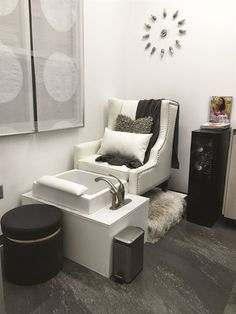 a white chair sitting next to a sink in a bathroom under a clock mounted on the wall