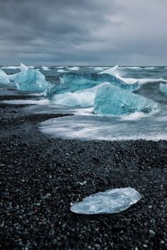 icebergs floating in the water on a rocky beach