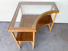 a wooden desk with a glass top on concrete flooring next to a white wall