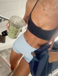 a woman in blue shorts holding a drink