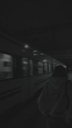 a person standing in front of a subway train at night with their back to the camera