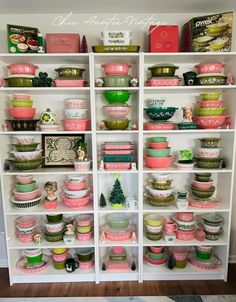 the shelves are filled with bowls and other kitchen items in pink, green and white