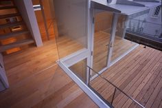 the inside of a house with wooden flooring and glass walls on top of it