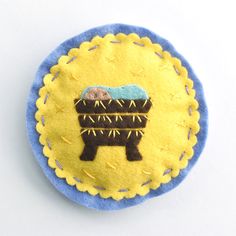 a blue and yellow brooch with an animal on it