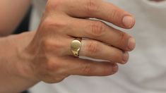 a woman's hand with a gold ring on her left and a white shirt on the right