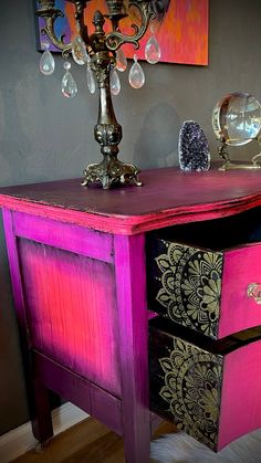 a pink and black dresser with a chandelier on top