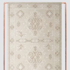 a beige rug with an intricate design on the front and back side, hanging from a copper frame