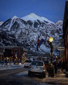 a car parked on the side of a road in front of snow covered mountains