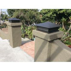 two black chimneys on top of a gray fence