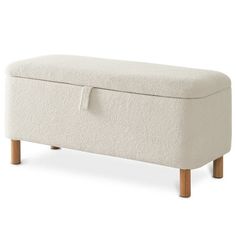 an upholstered bench with wooden legs and a cushion on the top, in white