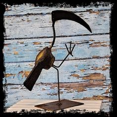 a metal bird sculpture on top of a wooden table