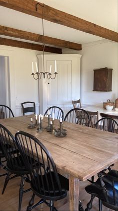 a wooden table with chairs around it in a room that has white walls and wood beams