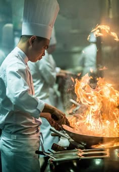 a chef is cooking on a grill with flames