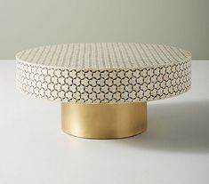 a white and gold ottoman sitting on top of a table