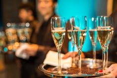 several glasses of champagne on a tray with people in the background