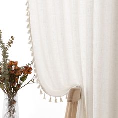 a vase filled with flowers next to a white curtain