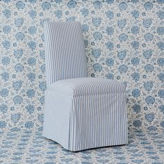 a blue and white striped chair against a floral wallpaper