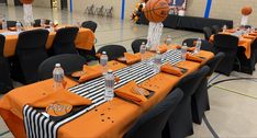 an indoor basketball themed party with black and orange tablecloths, centerpieces, and decorations