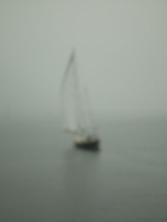 a sailboat sailing in the foggy ocean