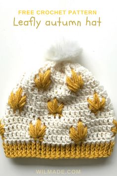 a crocheted beanie with yellow leaves on the front and white brim