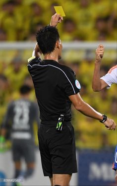 two soccer players giving each other a yellow card