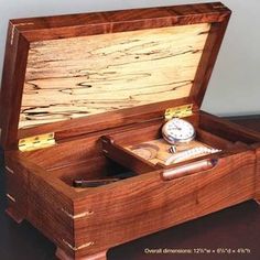 a wooden box with a watch inside on a table next to a clock and other items