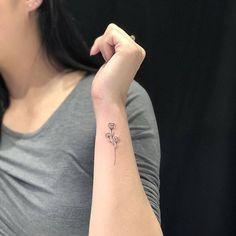 a woman's arm with a small flower tattoo on the left side of her arm