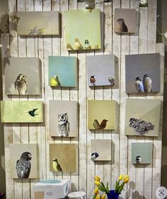 several birds are displayed on the wall behind a vase with yellow flowers and tulips