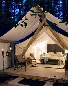 a bed sitting inside of a tent next to a forest