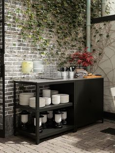 a table with plates and cups on it in front of a brick wall