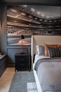 a bedroom with a bed, night stand and painting on the wall above it that has a football field