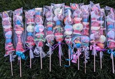 a bunch of lollipops that are sitting in the grass with ribbons on them