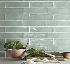 some vegetables are sitting on a counter in front of a blue brick backsplash