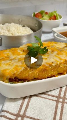 a casserole dish with cheese and vegetables on the side