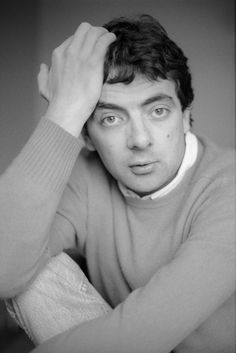 a black and white photo of a man with his hand on his head looking at the camera